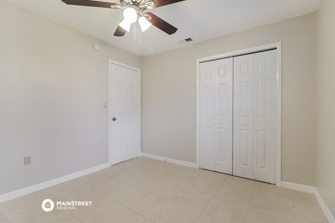 the spacious living room with two closets and a ceiling fan