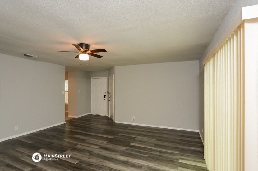 an empty living room with wood floors and a ceiling fan