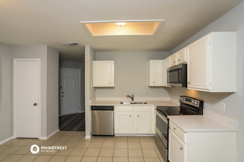 a kitchen with white cabinets and a stove and a microwave