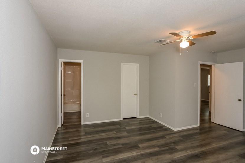 a living room with a ceiling fan and a door to a bathroom