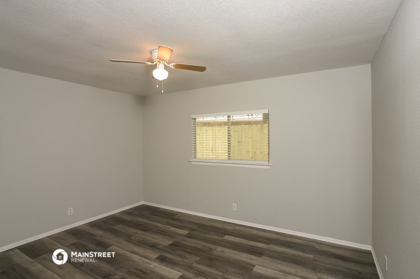 the interior of a bedroom with a ceiling fan and a window