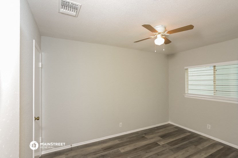 the interior of a bedroom with a ceiling fan and a window