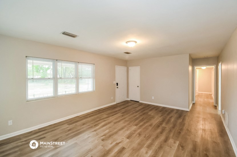 the spacious living room with wood flooring and a large window