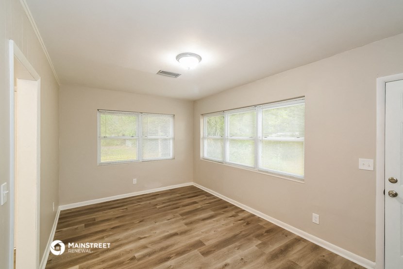 the spacious living room with hardwood flooring and two windows