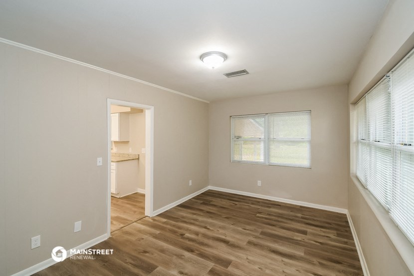 the spacious living room with wood flooring and a large window