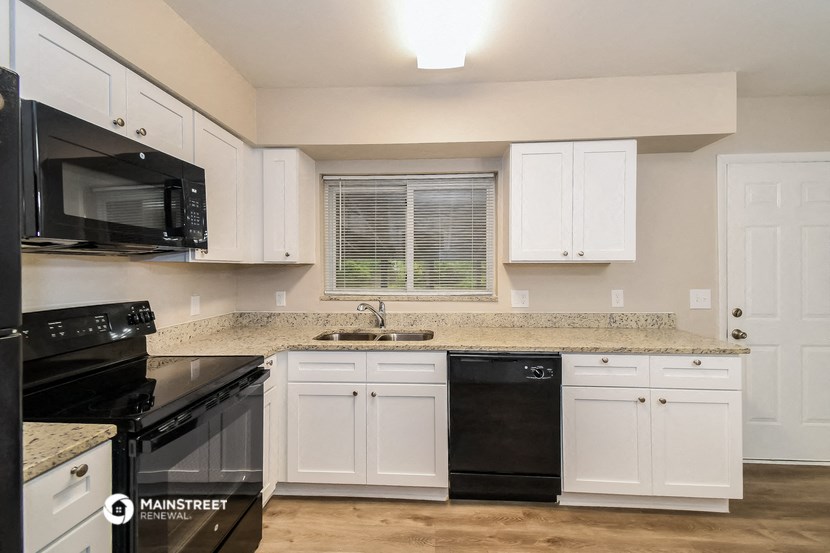 a kitchen with white cabinets and black appliances