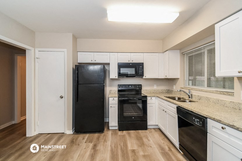 a kitchen with white cabinets and black appliances