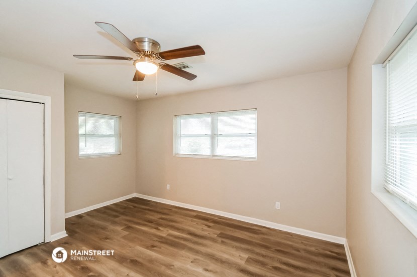 a bedroom with a ceiling fan and two windows