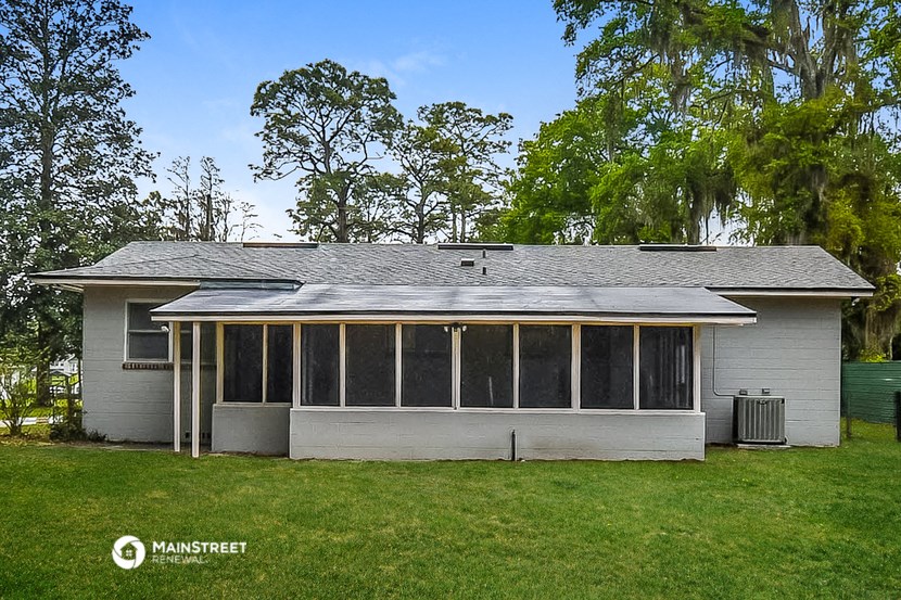 a white house with large windows on the side of a lawn