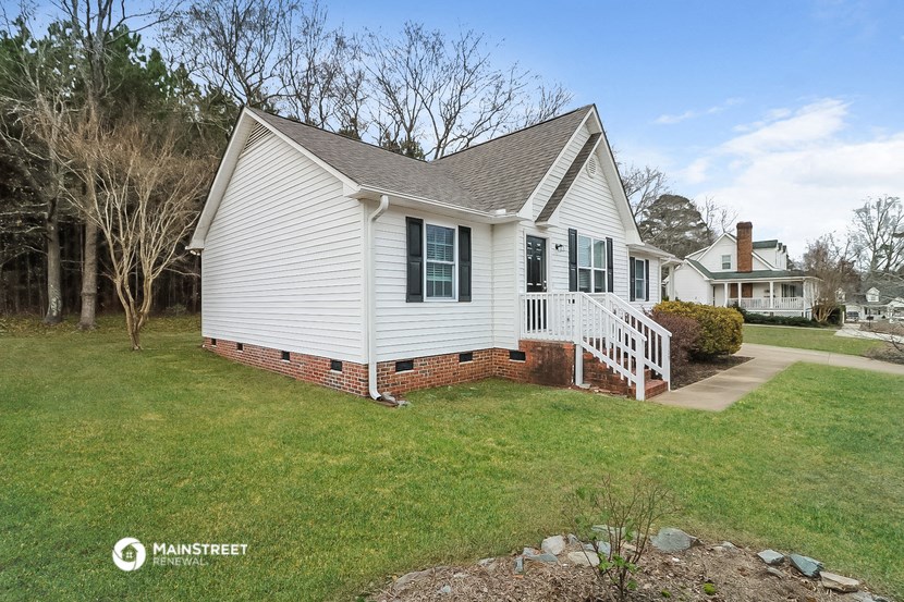 a white house with green shutters and a yard and a pathway