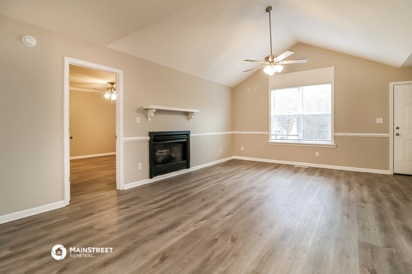 an empty living room with a fireplace and a ceiling fan