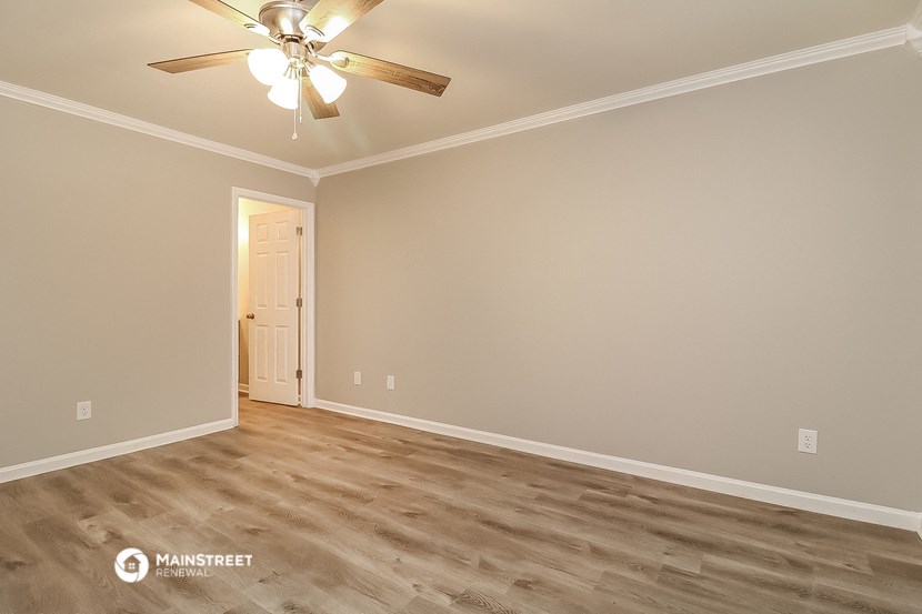 the spacious living room with wood flooring and a ceiling fan