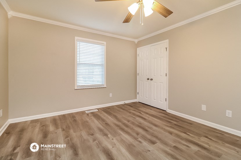 the bedroom of a house with a ceiling fan and a door