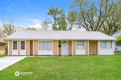 a white and tan house with white doors and a lawn