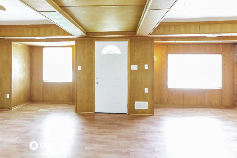 an empty room with a door and two windows