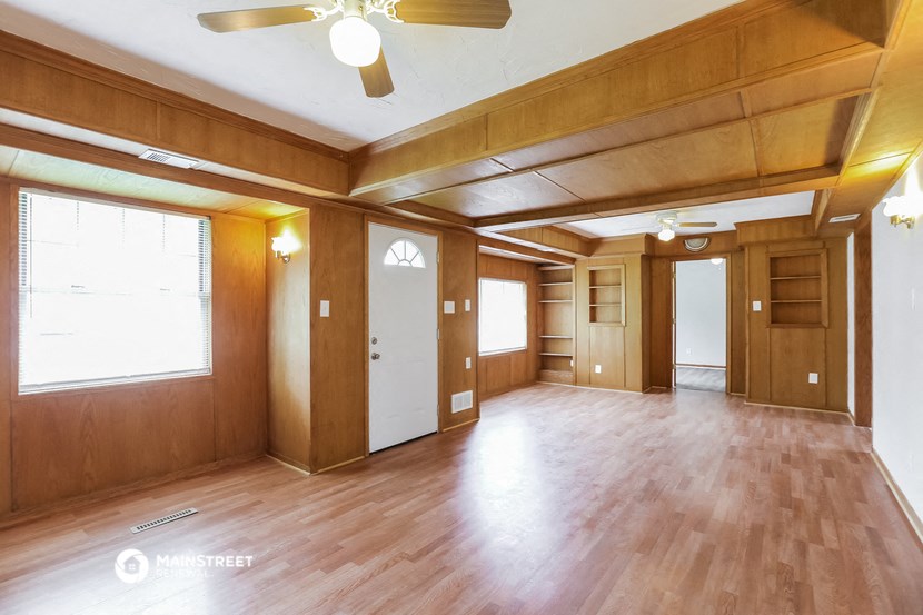 an empty living room with wood floors and a ceiling fan