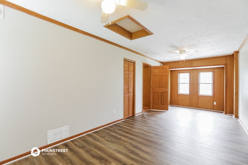 the living room of an empty house with white walls and wood floors