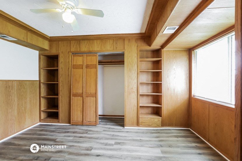 an empty room with wooden shelves and a ceiling fan