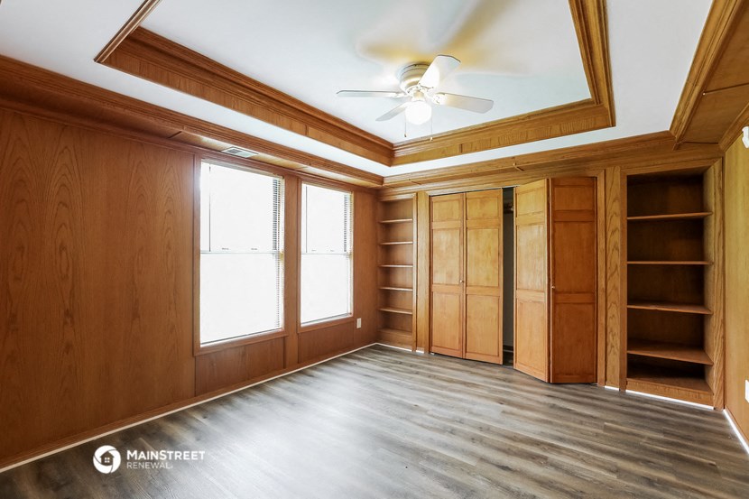 an empty living room with wood paneling and a ceiling fan