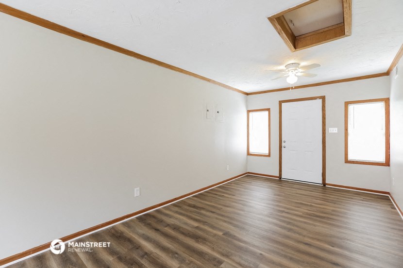 the living room of an empty house with wood flooring and a ceiling fan
