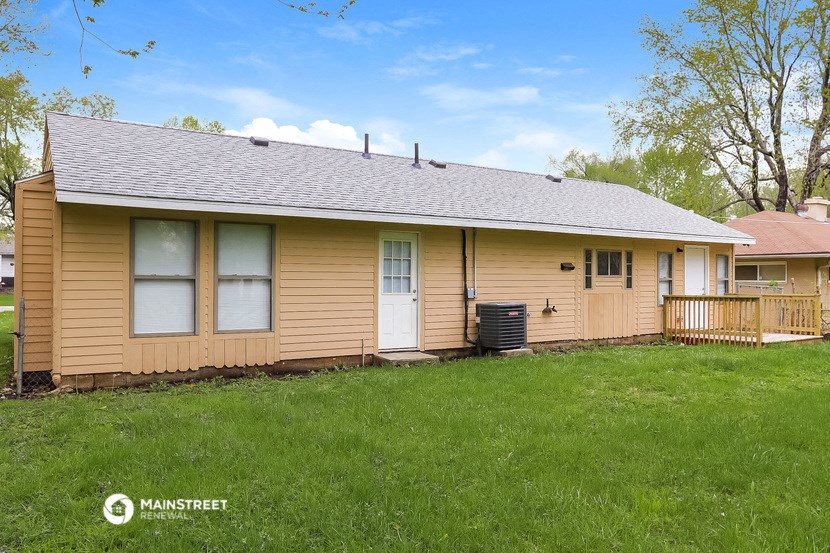 the front of a yellow house with a porch and a green lawn