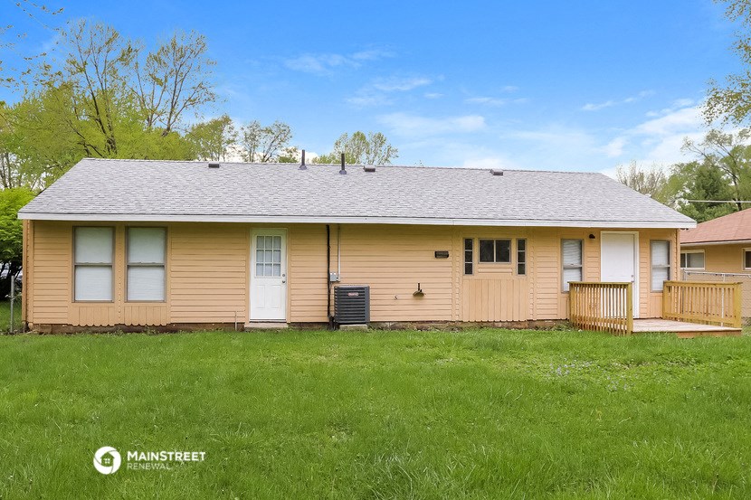 the front of a yellow house with a grassy yard