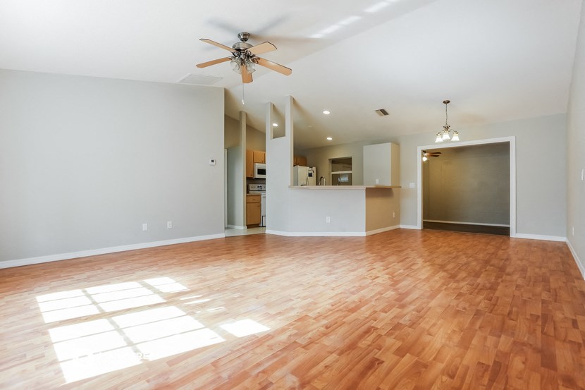 an empty living room with wood flooring and a ceiling fan
