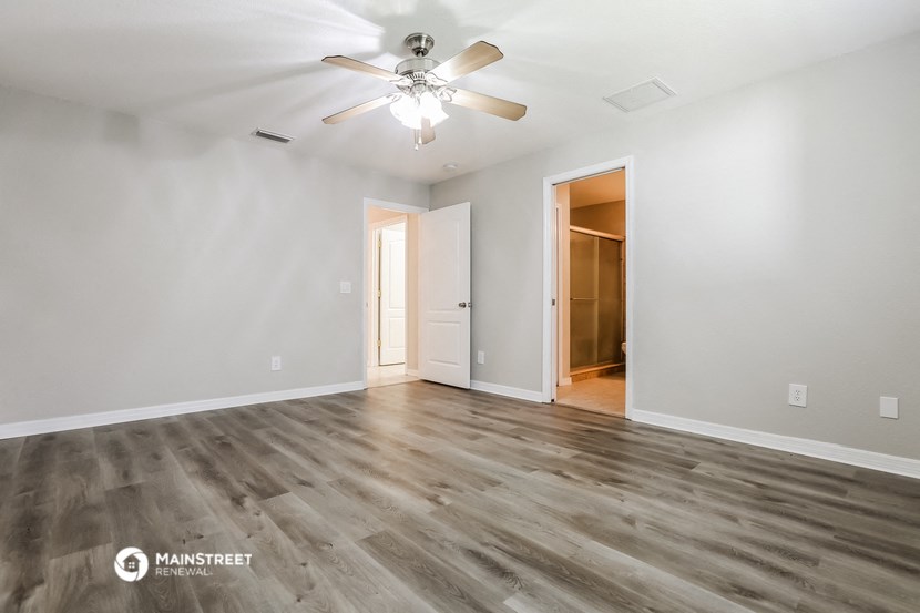 the living room of an empty house with a ceiling fan