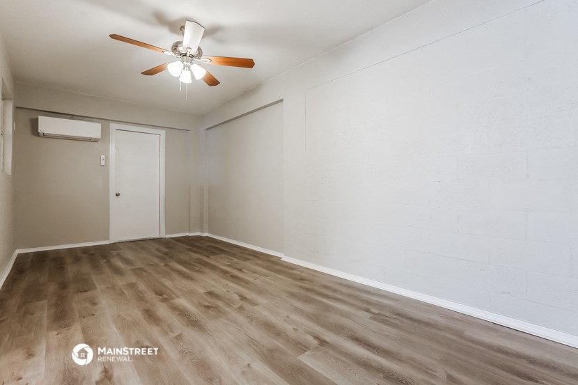 the living room of an apartment with wood flooring and a ceiling fan