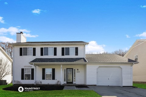 a white house with black shutters and a garage door