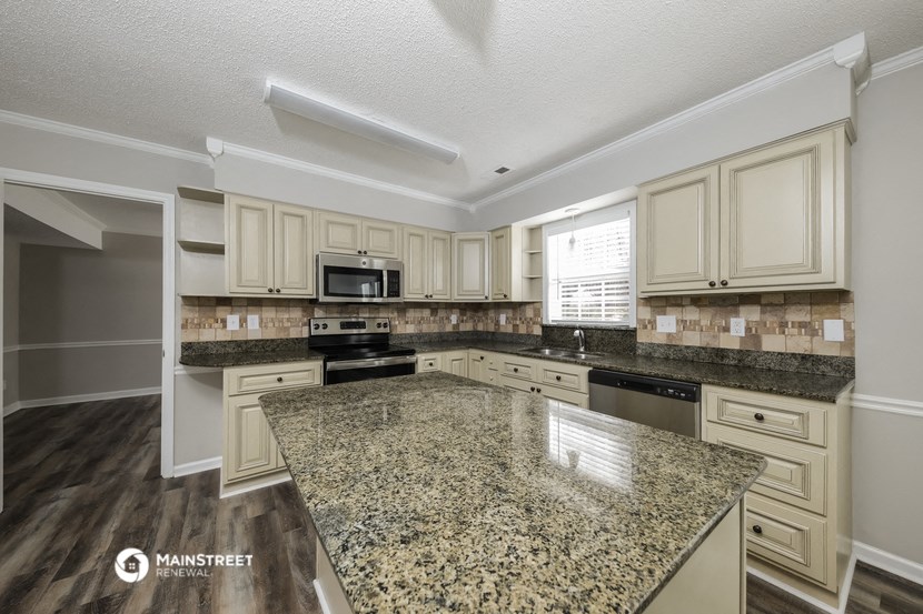 the kitchen has granite counter tops and white cabinets