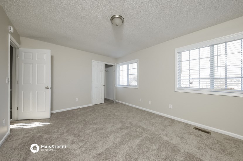 the spacious living room with carpeted flooring and windows