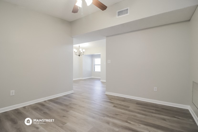 the living room and dining room with white walls and wood flooring