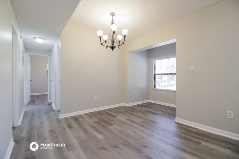 an empty living room with a chandelier and a window