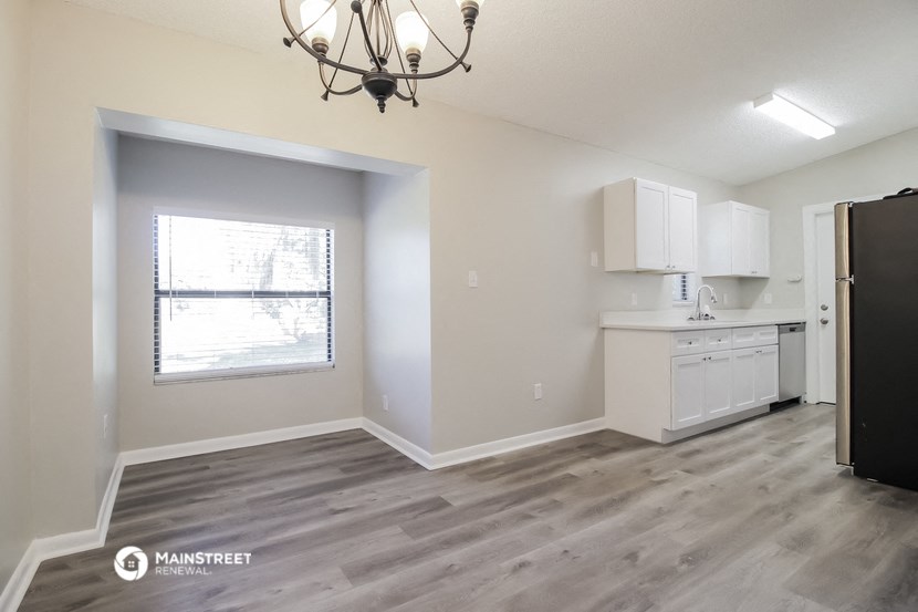 an empty kitchen with white cabinets and a window