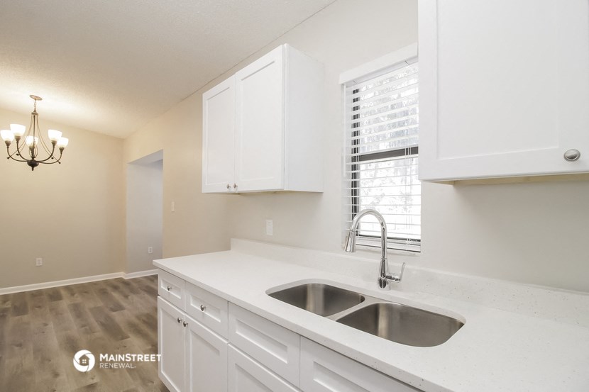 a white kitchen with a sink and a window