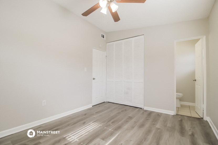 a living room with a ceiling fan and a door to a bathroom
