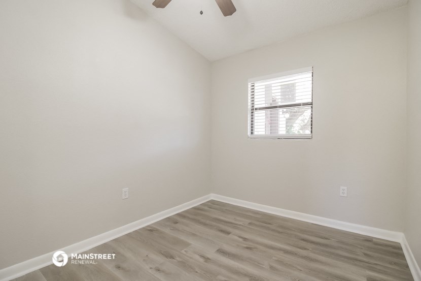 an empty room with wood flooring and a window