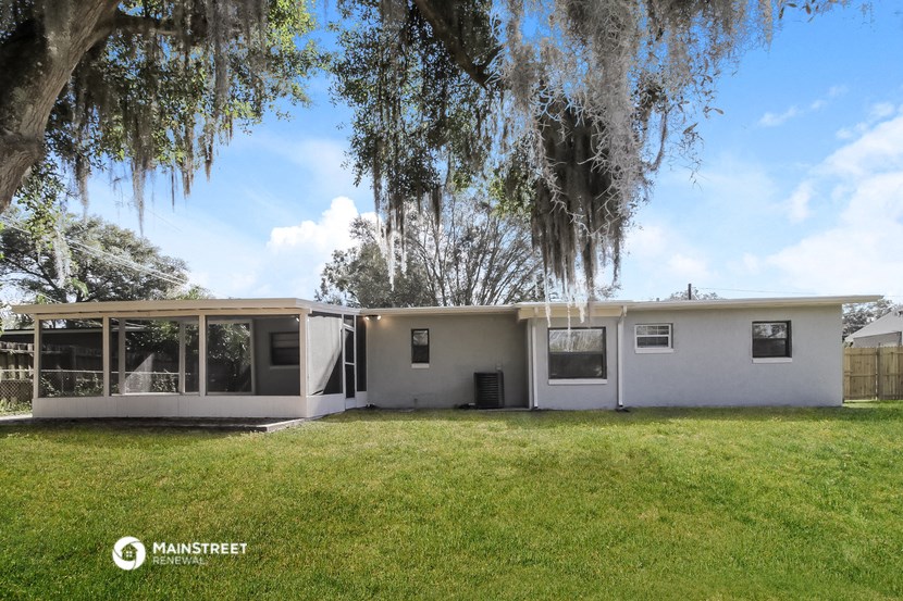 the exterior of a white house with a lawn and trees