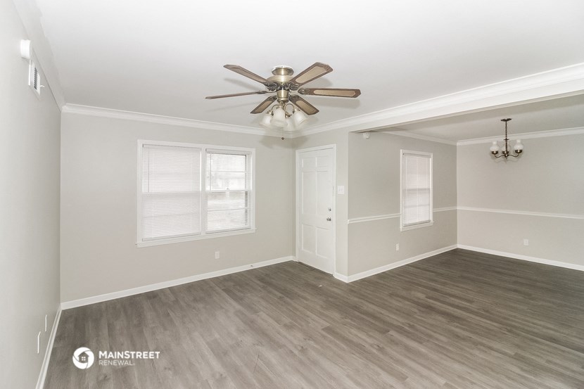 an empty living room with a ceiling fan and a window