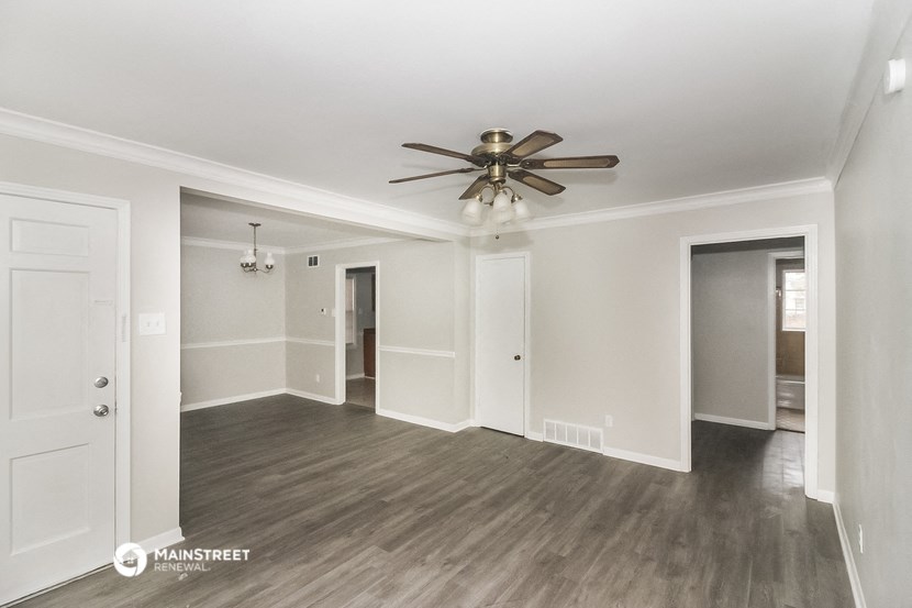 a living room with white walls and a ceiling fan