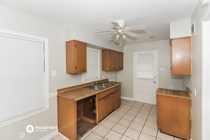 a kitchen with wooden cabinets and a sink and a ceiling fan