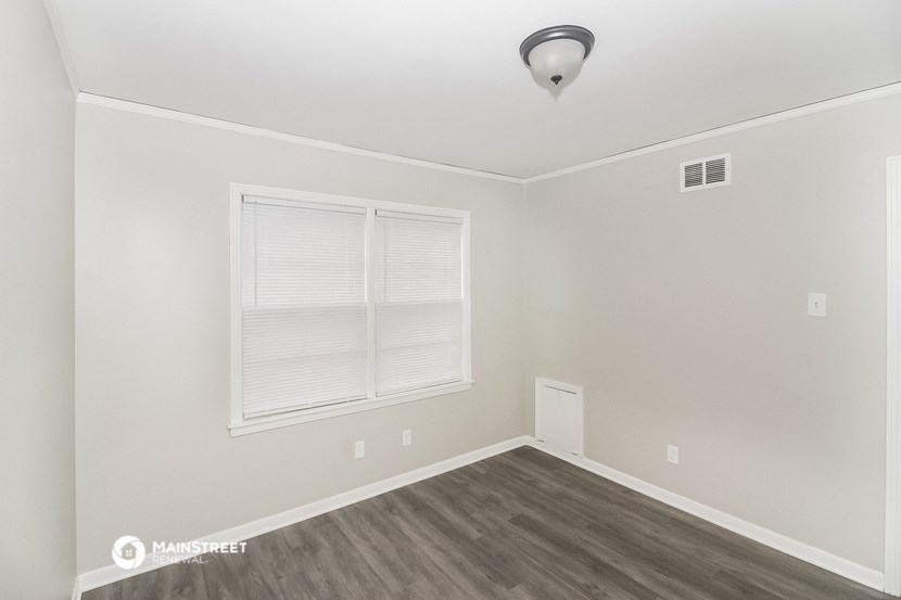 the living room of a home with a large window and wood floors