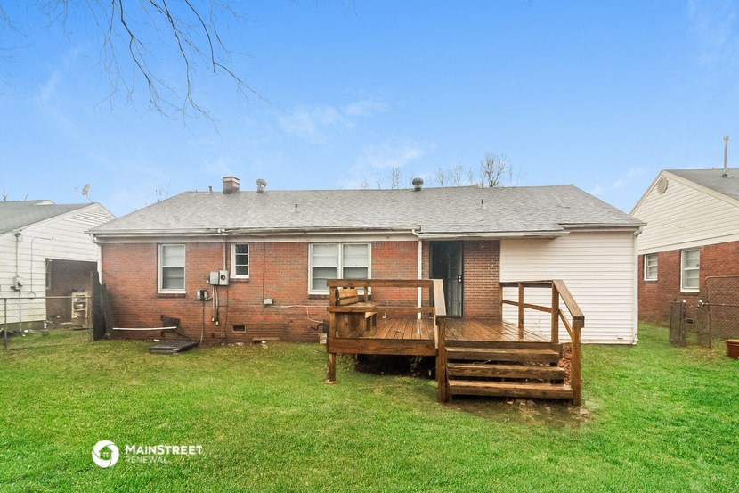 a brick house with a wooden deck in the yard