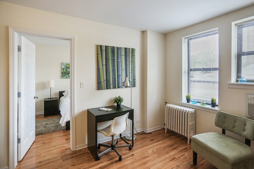 a living room with a desk and a chair and a bedroom