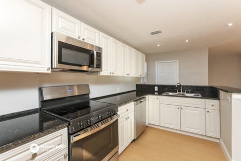a kitchen with white cabinets and black counter tops and a stove and microwave