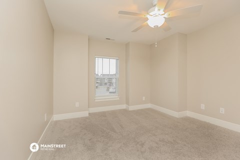 an empty living room with a ceiling fan and a window