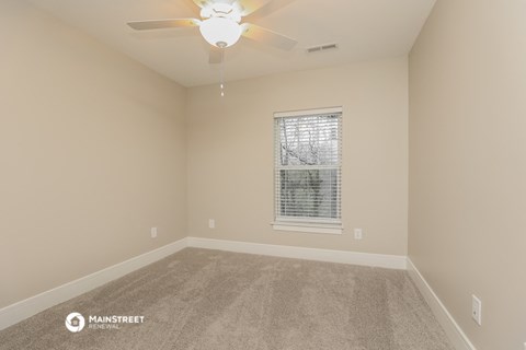 an empty room with a ceiling fan and a window