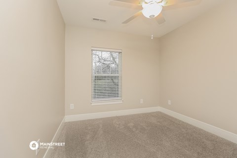 a empty room with a ceiling fan and a window