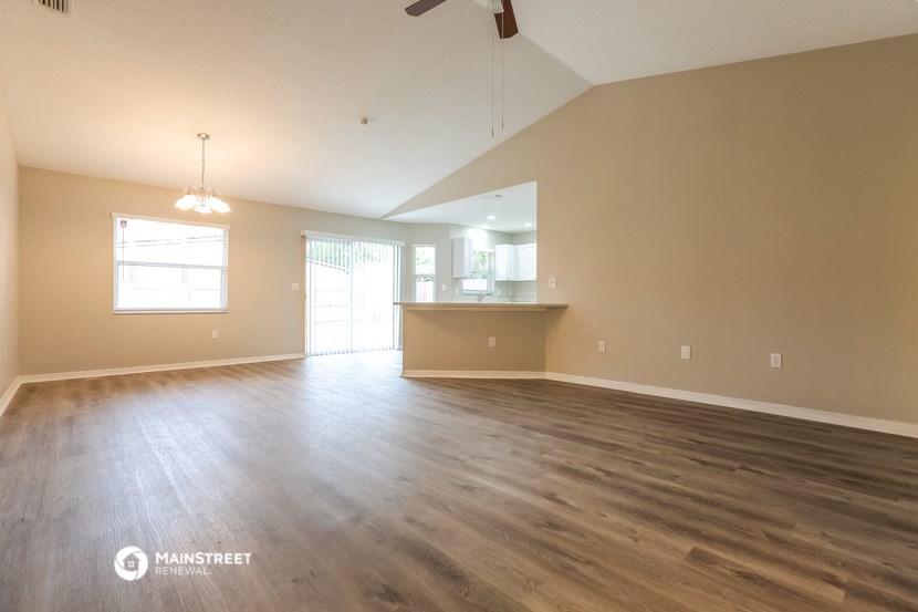 the living room and kitchen of an empty house with wood flooring